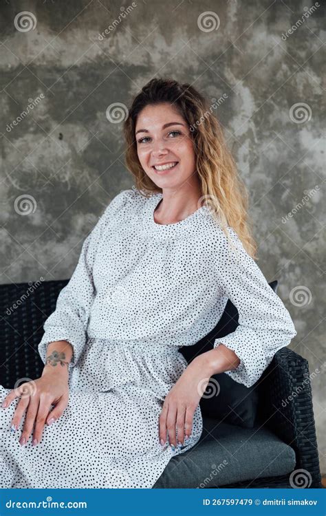 Une Belle Femme Assise Sur Une Chaise Dans Une Salle Grise Image Stock