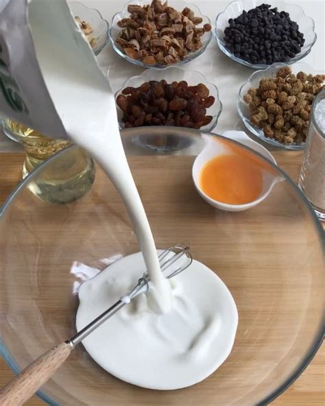 Milk Being Poured Into A Glass Bowl Filled With Nuts And Raisins