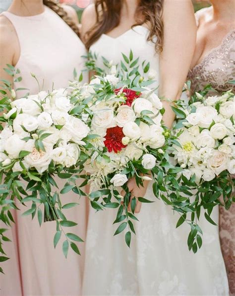 The Bridesmaids Are Holding Their Bouquets With White And Red Flowers