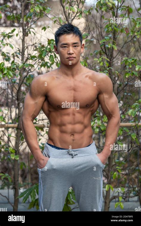 A Muscular Male Japanese Amateur Bodybuilder Poses Outdoors In A Street