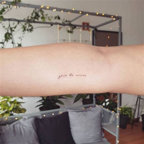 "Joie de vivre" lettering tattoo on the inner forearm.