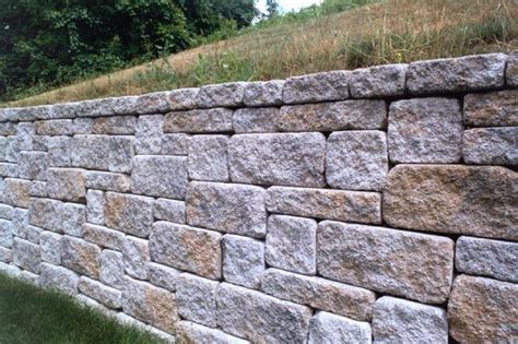 A Stone Wall With Grass And Trees In The Background