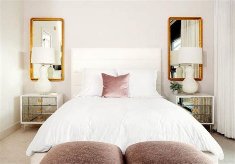 Curved Gold Framed Mirrors Hang Above Antique Mirrored Nightstands