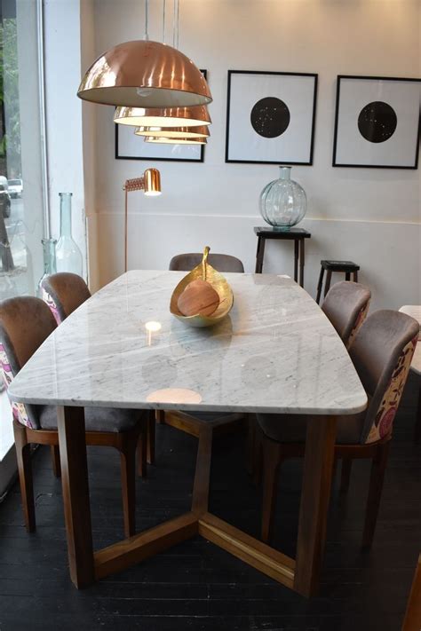 A Marble Dining Table Surrounded By Brown Leather Chairs