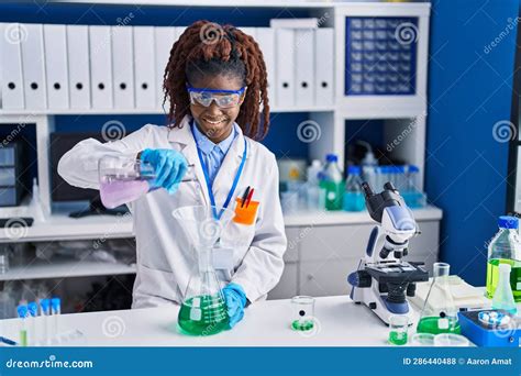 African American Woman Scientist Pouring Liquid On Test Tube At