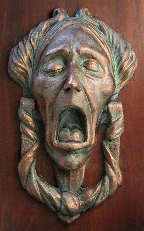 A Close Up Of A Metal Face On A Wooden Door With It S Mouth Open