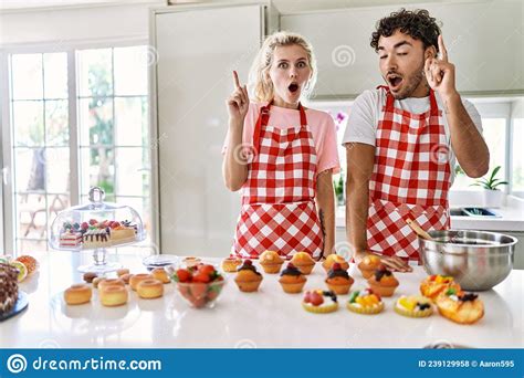 Couple Of Wife And Husband Cooking Pastries At The Kitchen Pointing Finger Up With Successful