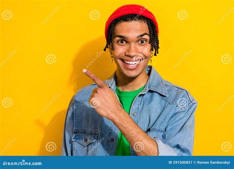 Photo Of Funky Cheerful Guy Dressed Denim Jacket Beanie Showing Finger Empty Space Isolated