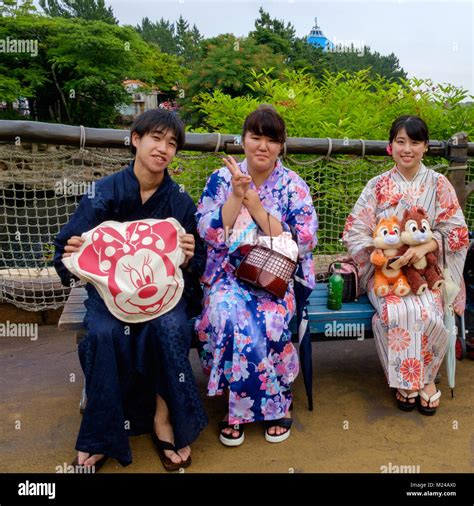 Tres jóvenes japoneses vestidos de kimonos sentado en un banco