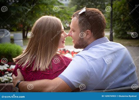 Couple In Love Is Sitting On A Bench Man And Woman Enjoy Each Other`s Conversation In The