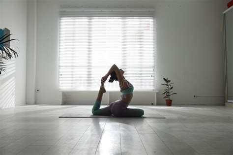 Woman Practicing One Legged King Pigeon Asana In Studio Eka Pada