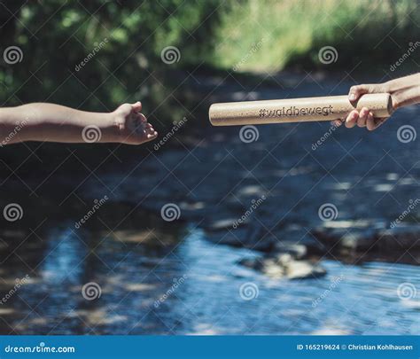 Two Kids Hands Reaching Each Other In Nature Infront Of Water Stock