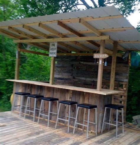 An Outdoor Bar Made Out Of Pallets And Wooden Planks With Stools Under It