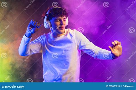 Positive Man Listening Music With Headphones Dancing On Dark Neon