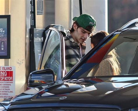 A Man And Woman Getting Out Of A Car At A Gas Station With The Door Open