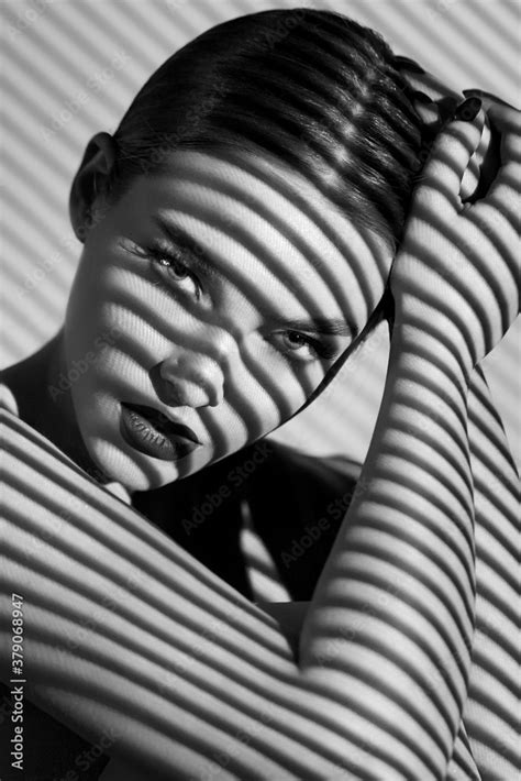 Black and white portrait of a beautiful woman with a shadow pattern on ...