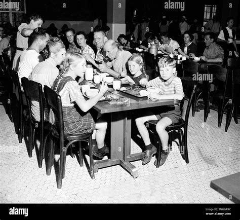 Children and adult immigrants detained at Ellis Island sit down to eat their noontime meal in ...