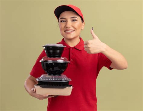 Free Photo Young Delivery Woman In Red Uniform And Cap Holding Stack