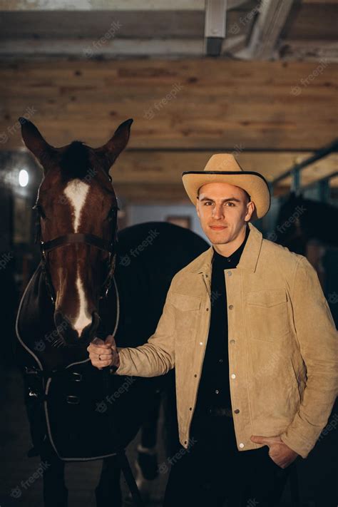 Premium Photo | Handsome young cowboy on a ranch with a horse