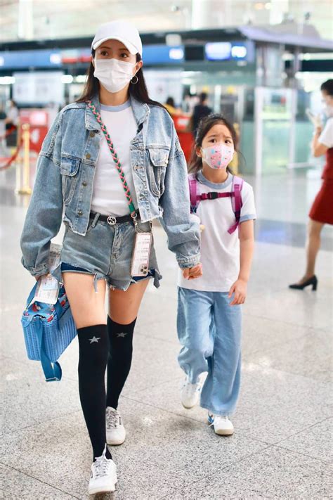 包文婧带着女儿穿靓丽牛仔现身机场， 女儿扎饺子丸子头眼神清灵！财经头条