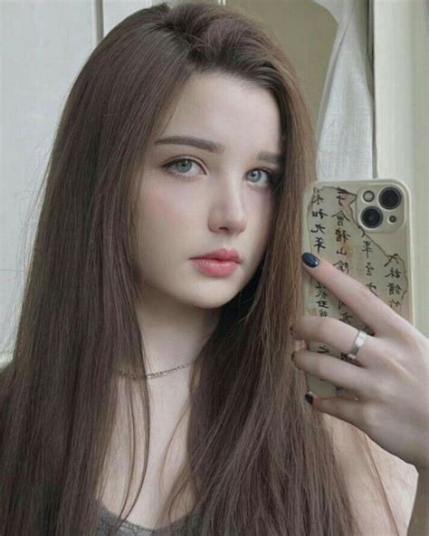 A Woman With Long Brown Hair Holding Up A Cell Phone In Front Of Her Face