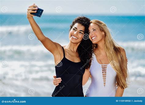 Two Women Taking Selfie Photograph With Smartphone In The Beach Stock