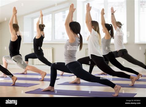 Group Of Young Sporty People Practicing Yoga Lesson Doing Warrior I