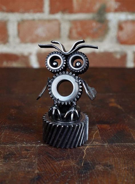 An Owl Figurine Sitting On Top Of A Metal Gear Cogwheel With Eyes Open