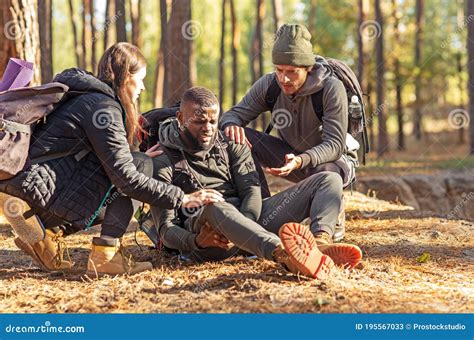 Friends Helping African Injured Guy While Hiking By Forest Stock Image Image Of Helping Fall