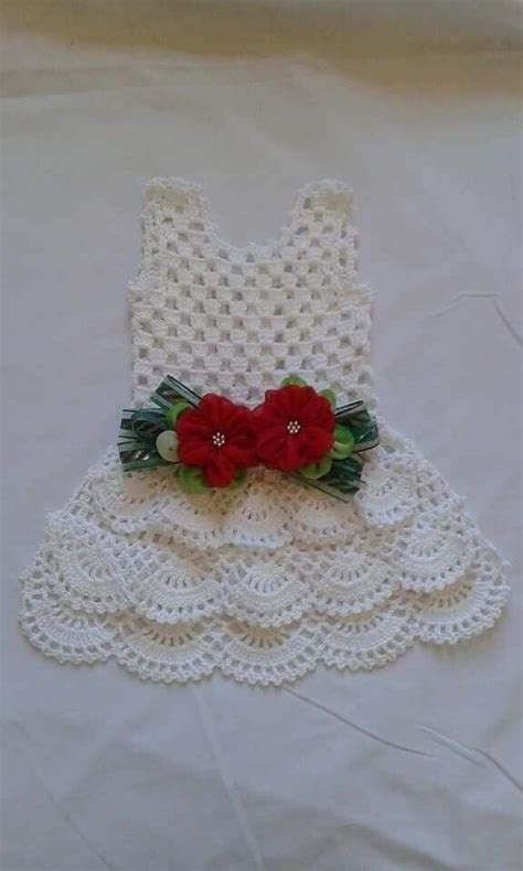 A White Dress With Red Flowers On The Front And Green Leaves On The