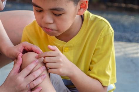 Premium Photo Cropped Hands Of Person Examining Injured Knee Of Boy