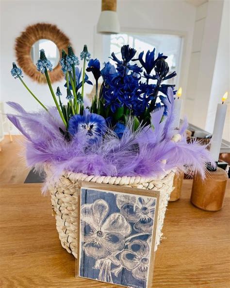 A Basket Filled With Blue Flowers And Purple Feathers