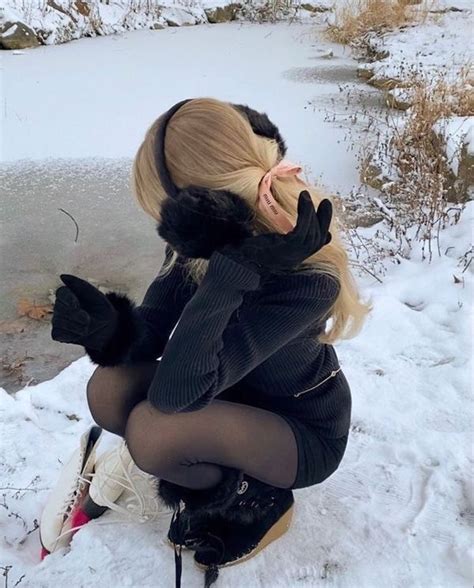 A Woman Sitting On Top Of A Snow Covered Ground Next To A Body Of Water