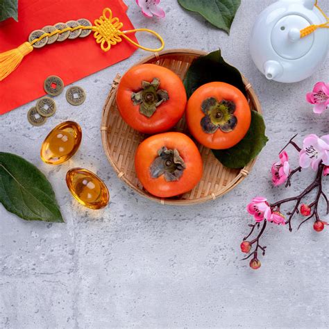 Top view of fresh sweet persimmons with leaves on gray table background