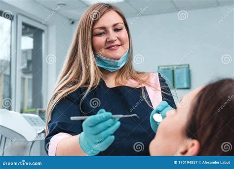 Portrait Of Happy Female Dentist In Mask Sitting Holding Dentist Tools