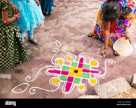 Indian woman making Dasara Rangoli festival coloured powder design. Puttaparthi, Andhra Pradesh ...