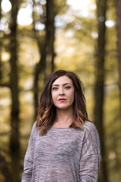 Premium Photo Portrait Of Young Woman Standing Against Trees At Forest