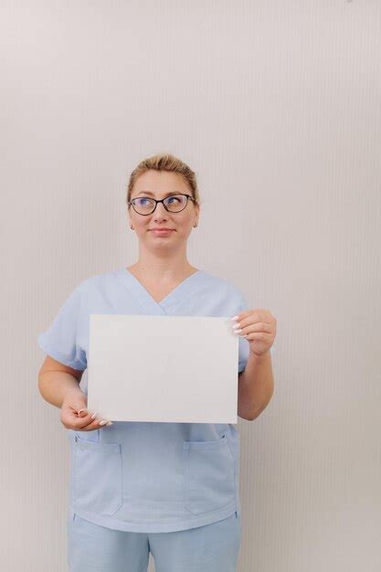 Retrato de una doctora con una túnica azul sosteniendo una hoja blanca