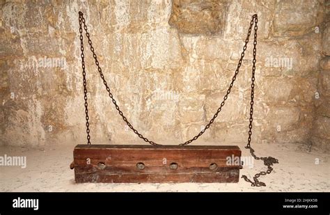 Old Wooden Shackles Fixed With Iron Chains To The Prison Wall In A