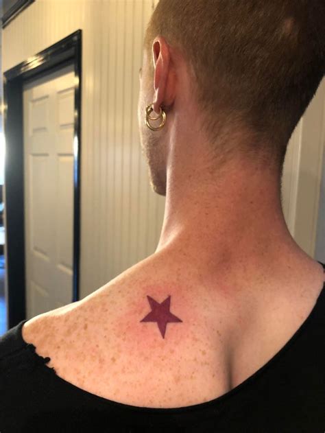 A Man With A Small Star Tattoo On His Back Shoulder And Neck Standing