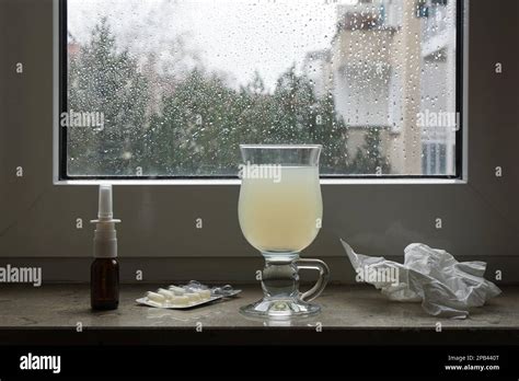 Common Cold Or Flu Remedy Hot Lemonade Nasal Spray Pills And Tissues On Window Sill Stock