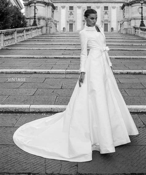 A Woman In A Long White Dress Standing On Some Steps With An Old