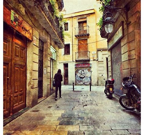 A Man Walking Down An Alley Way Between Two Parked Motor Scooter S