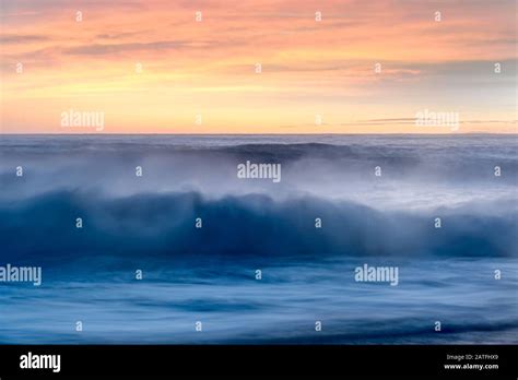 Breaking Waves With A Misty Spray At Sunset Over The Sea Under A