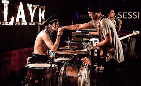 Two Men Playing Drums In Front Of A Sign That Says Layh On It And