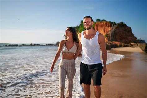 Romantic Couple Walks On Beach At Sunset Holding Hands Newlyweds On