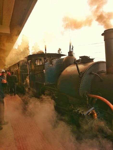 Pessoas de pé junto ao trem a vapor na plataforma da estação