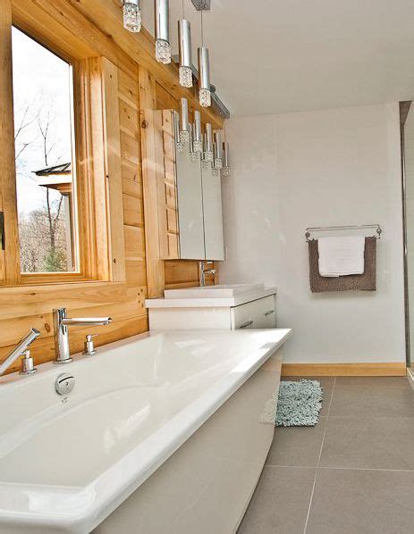 a large white bath tub sitting next to a walk in shower and wooden paneled walls