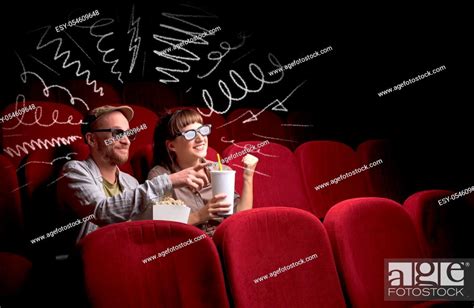 Young Cute Couple Sitting In Cinema And Eating Popcorn While Watching