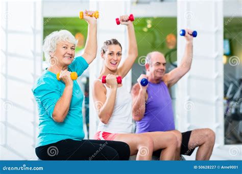 Seniors With Trainer In Gym At Sport Lifting Barbell Stock Image